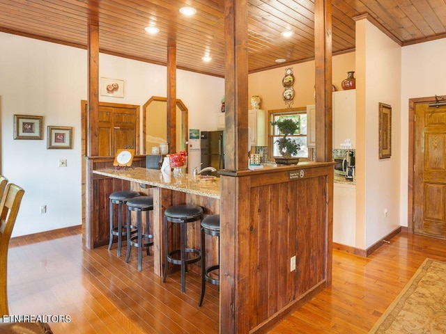 kitchen featuring light hardwood / wood-style flooring, kitchen peninsula, light stone countertops, and wooden ceiling