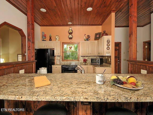 kitchen with tasteful backsplash, wood ceiling, light stone counters, and black appliances