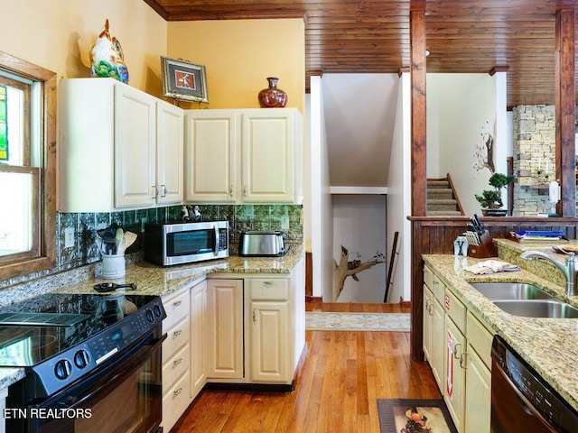 kitchen featuring sink, decorative backsplash, light stone counters, black appliances, and wooden ceiling