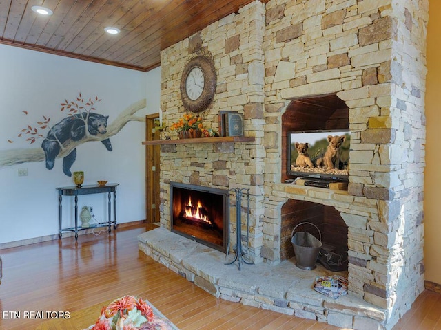 living room with hardwood / wood-style flooring, crown molding, wooden ceiling, and a fireplace