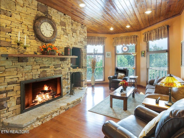 living room featuring wood ceiling, ornamental molding, wood-type flooring, and a stone fireplace