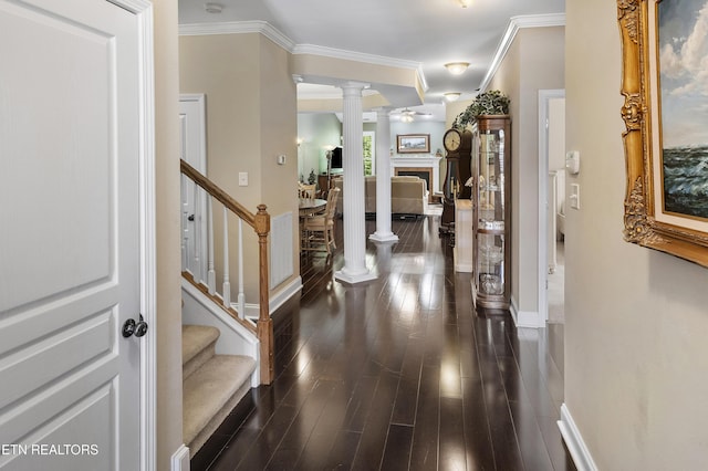 entryway featuring dark wood-type flooring, crown molding, and ornate columns