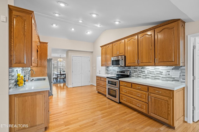 kitchen with lofted ceiling, sink, appliances with stainless steel finishes, light hardwood / wood-style floors, and backsplash