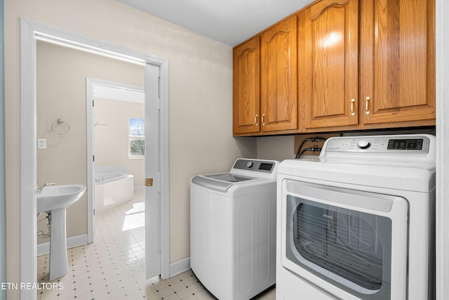 clothes washing area featuring cabinets and washer and clothes dryer