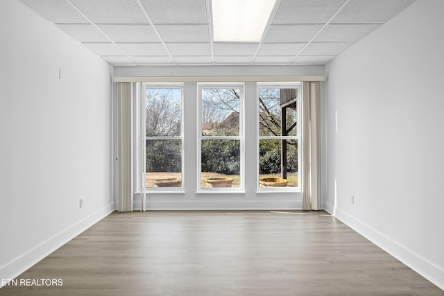 empty room with wood-type flooring and a drop ceiling