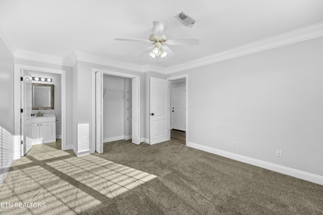 unfurnished bedroom featuring ensuite bathroom, ornamental molding, ceiling fan, dark carpet, and a closet