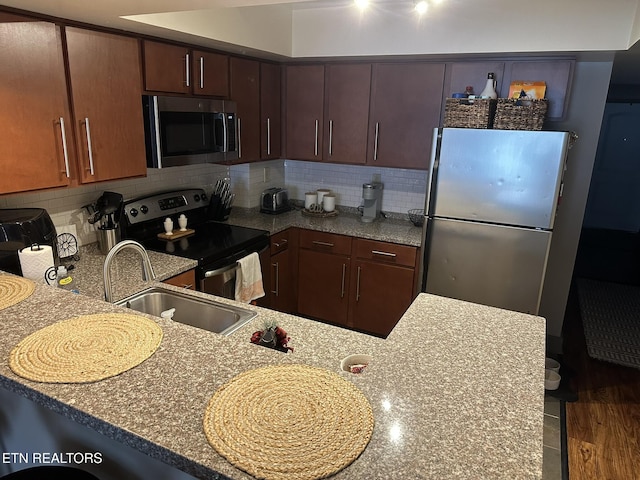 kitchen with light stone countertops, appliances with stainless steel finishes, sink, and decorative backsplash