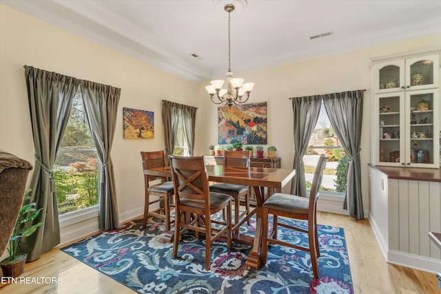 dining area featuring an inviting chandelier, light hardwood / wood-style flooring, ornamental molding, and plenty of natural light