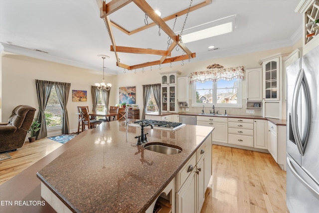 kitchen with dark stone countertops, appliances with stainless steel finishes, sink, and a center island with sink