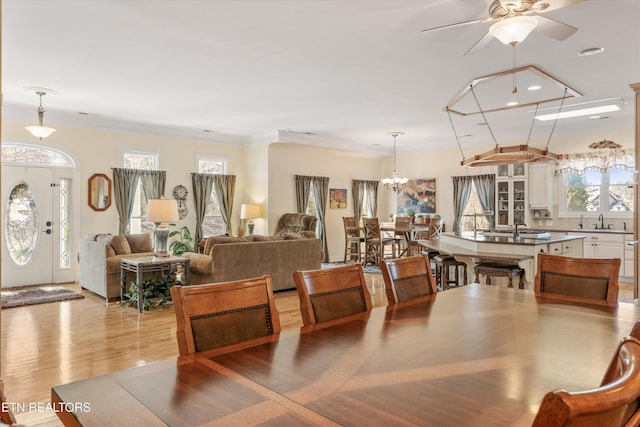 dining room with a healthy amount of sunlight, sink, crown molding, and light wood-type flooring