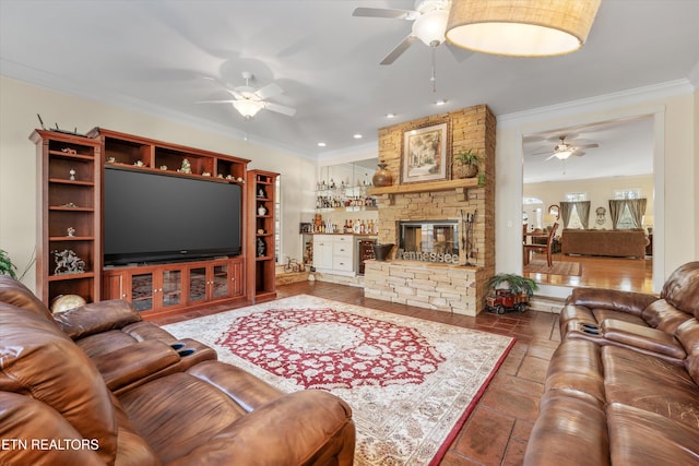 living room featuring ceiling fan, ornamental molding, and a stone fireplace