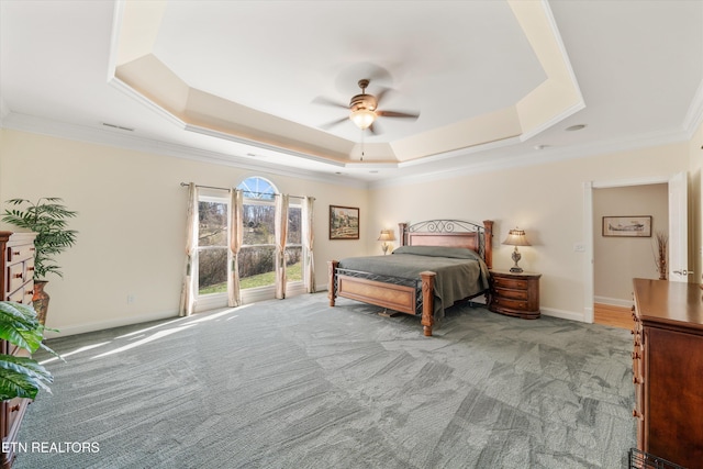 carpeted bedroom featuring ornamental molding, ceiling fan, and a tray ceiling