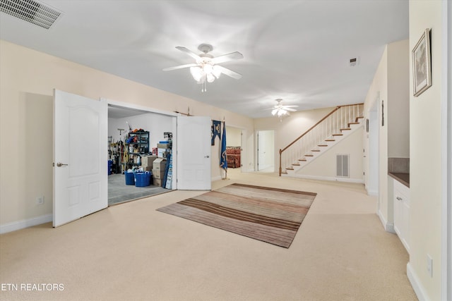 basement with ceiling fan and light colored carpet