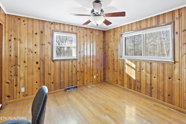 interior space with wood-type flooring, ornamental molding, and ceiling fan