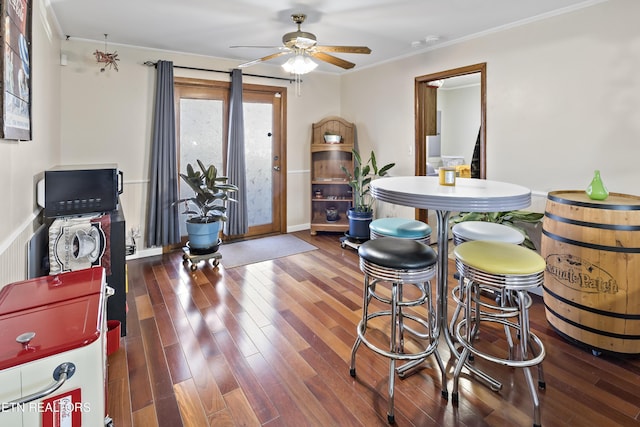 dining room with dark wood-type flooring, ornamental molding, and ceiling fan