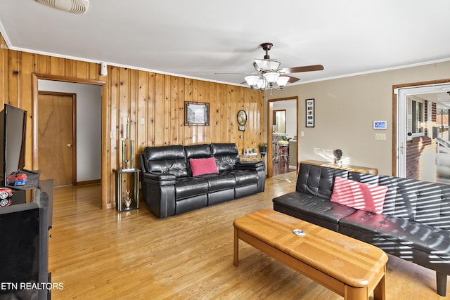 living room featuring crown molding, wood-type flooring, ceiling fan, and wood walls