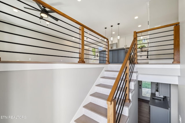 stairway with hardwood / wood-style flooring and ceiling fan