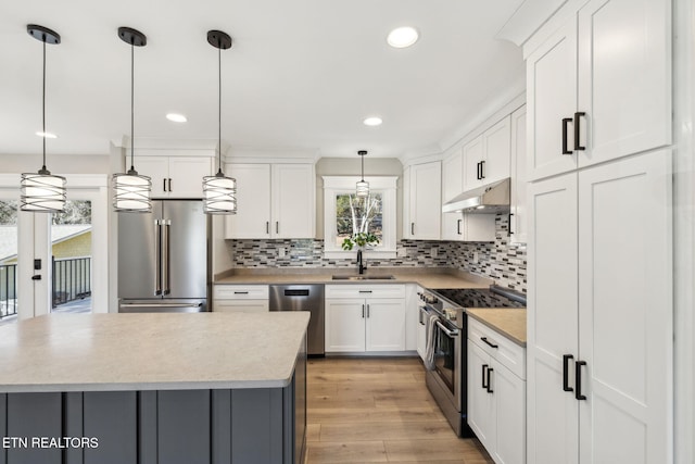 kitchen with hanging light fixtures, appliances with stainless steel finishes, and white cabinets