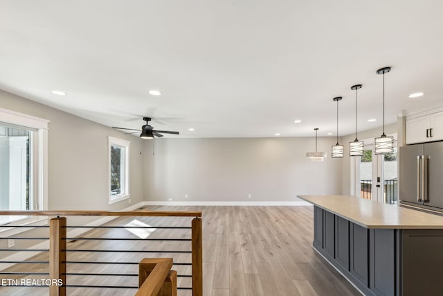 kitchen with white cabinetry, high end refrigerator, hanging light fixtures, light hardwood / wood-style flooring, and a kitchen island