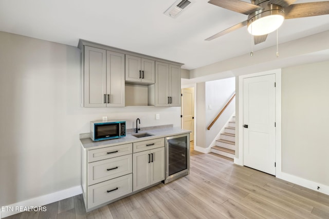 kitchen with wine cooler, sink, light hardwood / wood-style flooring, and gray cabinetry