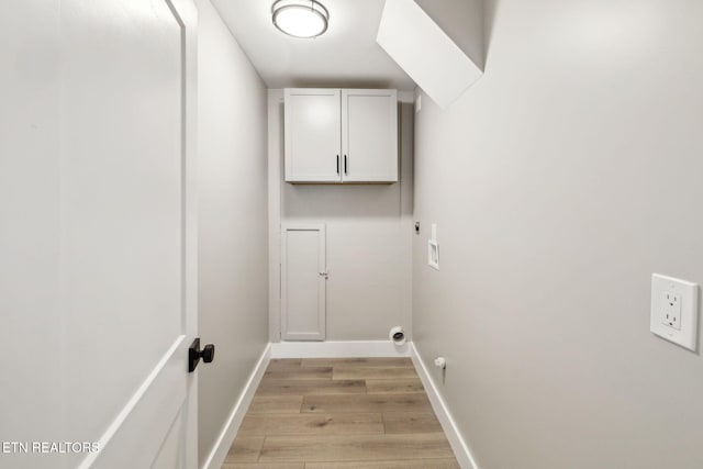 clothes washing area with cabinets, hookup for a washing machine, and light hardwood / wood-style flooring