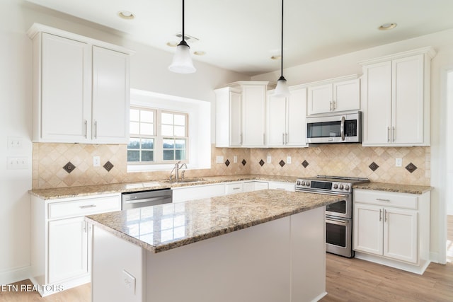 kitchen with pendant lighting, sink, appliances with stainless steel finishes, white cabinetry, and a center island