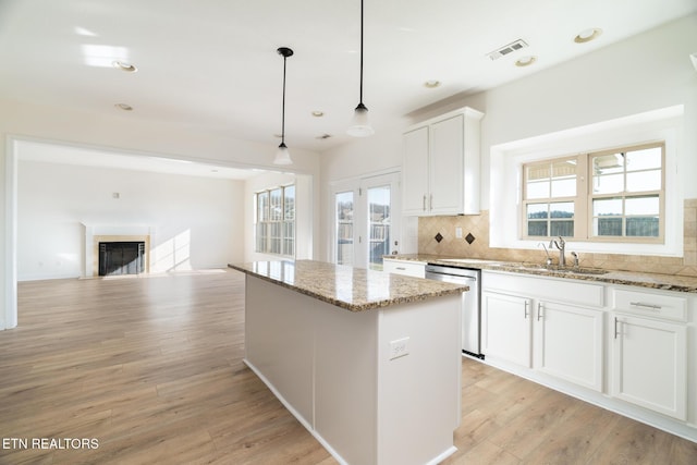 kitchen with sink, dishwasher, white cabinetry, a center island, and decorative light fixtures