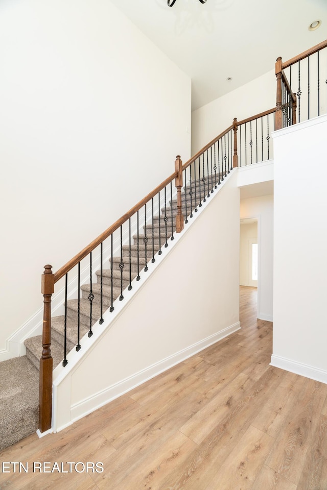 stairway featuring a high ceiling and wood-type flooring