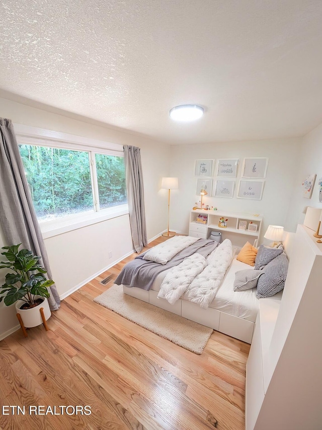 bedroom featuring hardwood / wood-style flooring and a textured ceiling