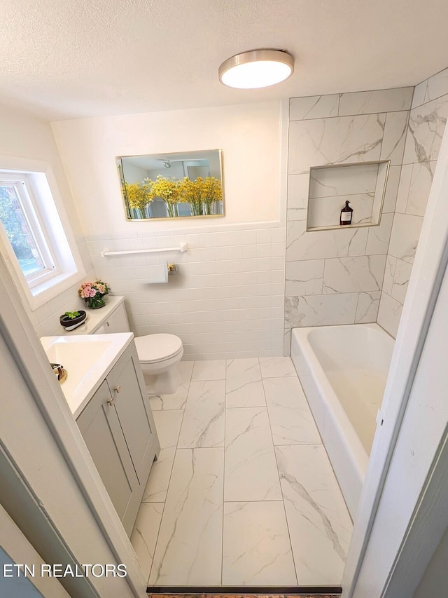 bathroom featuring tile walls, a bathtub, vanity, a textured ceiling, and toilet