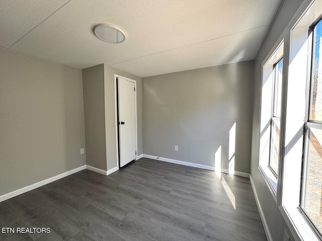 unfurnished room with dark hardwood / wood-style floors and a textured ceiling