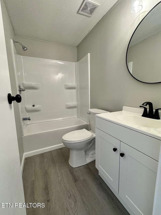 full bathroom featuring bathtub / shower combination, hardwood / wood-style flooring, vanity, toilet, and a textured ceiling