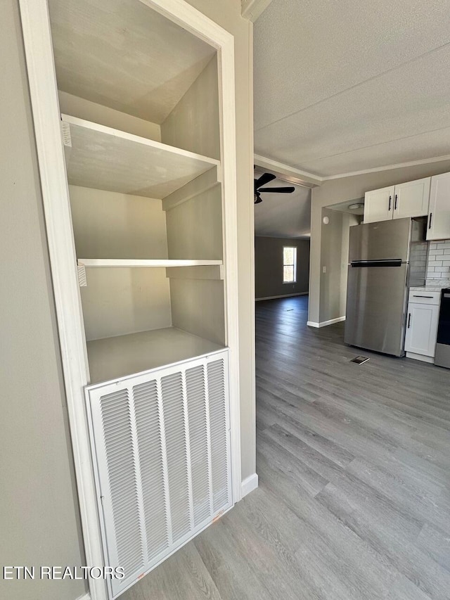 interior space featuring stainless steel refrigerator, ceiling fan, stove, backsplash, and wood-type flooring