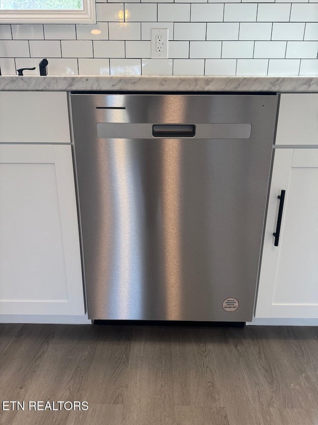 details featuring dark hardwood / wood-style flooring, stainless steel dishwasher, and white cabinets