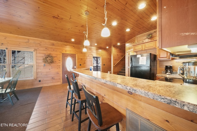 kitchen featuring black fridge, wood ceiling, decorative light fixtures, a kitchen breakfast bar, and kitchen peninsula