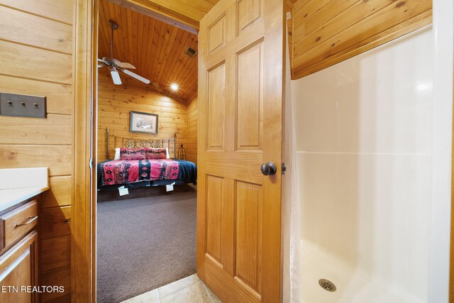 bathroom with vaulted ceiling, wood walls, vanity, ceiling fan, and wood ceiling