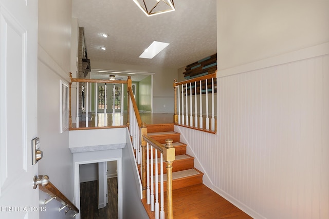 stairs with hardwood / wood-style flooring, a skylight, and a textured ceiling