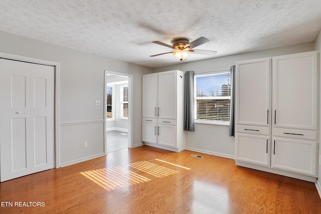 unfurnished bedroom featuring ceiling fan, a textured ceiling, and light hardwood / wood-style floors