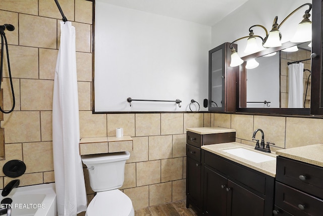 full bathroom featuring shower / tub combo with curtain, tile walls, hardwood / wood-style floors, vanity, and toilet