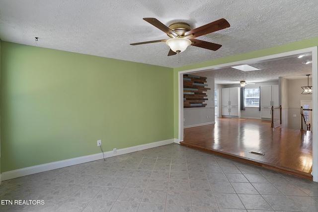 spare room with a textured ceiling, a skylight, and ceiling fan