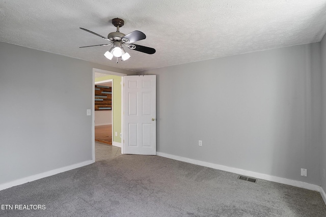 empty room featuring ceiling fan, light colored carpet, and a textured ceiling