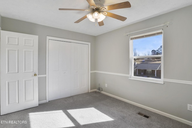 unfurnished bedroom with ceiling fan, carpet, a closet, and a textured ceiling