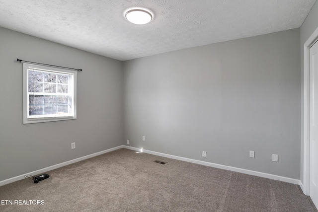 unfurnished room with carpet and a textured ceiling