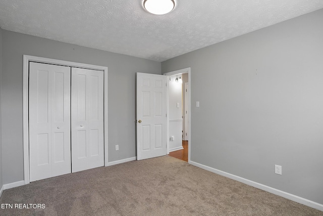 unfurnished bedroom with a closet, light carpet, and a textured ceiling