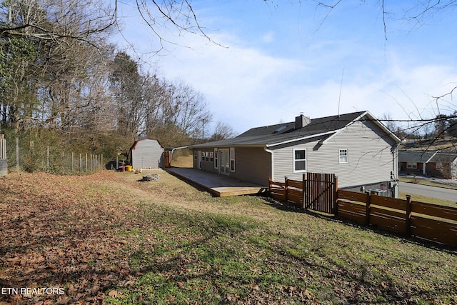 back of house featuring a shed, a wooden deck, and a yard