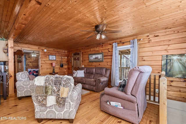 living room featuring ceiling fan, wooden walls, wooden ceiling, and light wood-type flooring