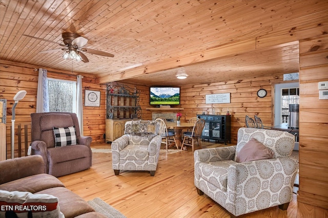 living room with ceiling fan, light wood-type flooring, wood ceiling, and wood walls