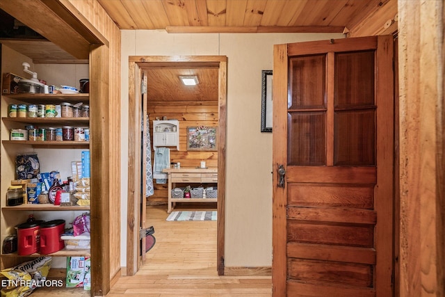 corridor featuring wood walls, light wood-type flooring, and wooden ceiling