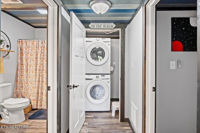 laundry area with stacked washer and dryer and wood-type flooring