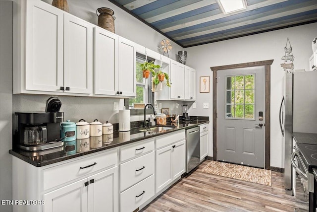 kitchen featuring stainless steel appliances, white cabinetry, sink, and a wealth of natural light